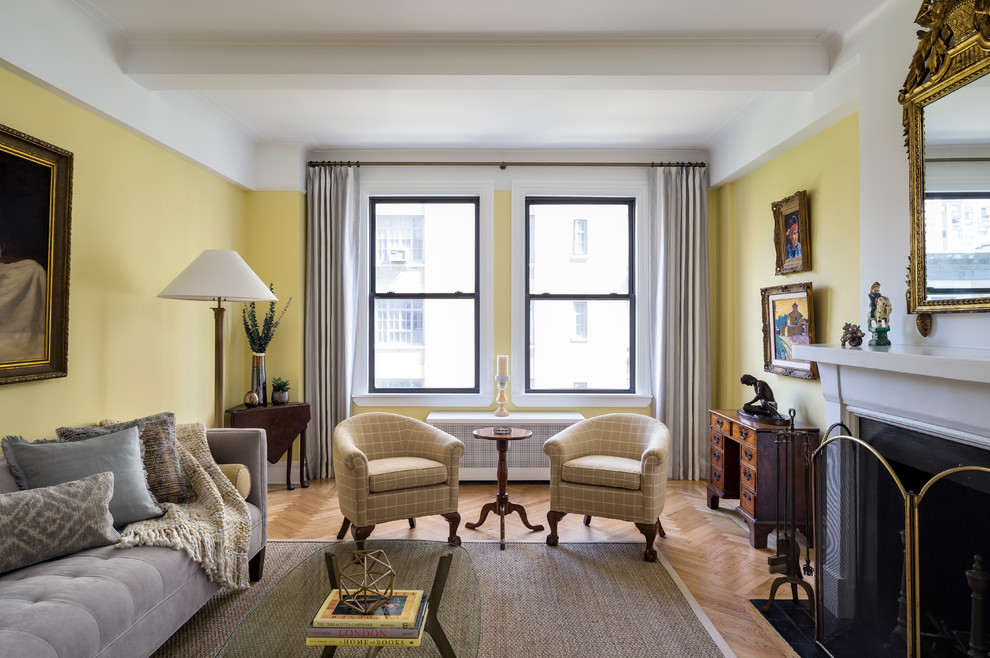 На фото: парадная, изолированная гостиная комната в стиле неоклассика (современная классика) с желтыми стенами, паркетным полом среднего тона, стандартным камином и коричневым полом с