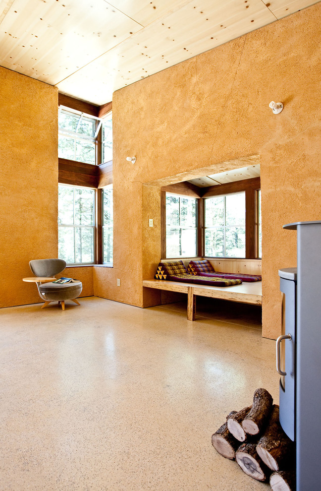 Foto di un piccolo soggiorno rustico aperto con pareti arancioni, nessuna TV, stufa a legna e pavimento in cemento