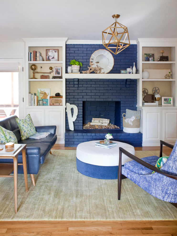 Идея дизайна: гостиная комната в стиле ретро с белыми стенами, паркетным полом среднего тона, стандартным камином, фасадом камина из кирпича, коричневым полом и синим диваном