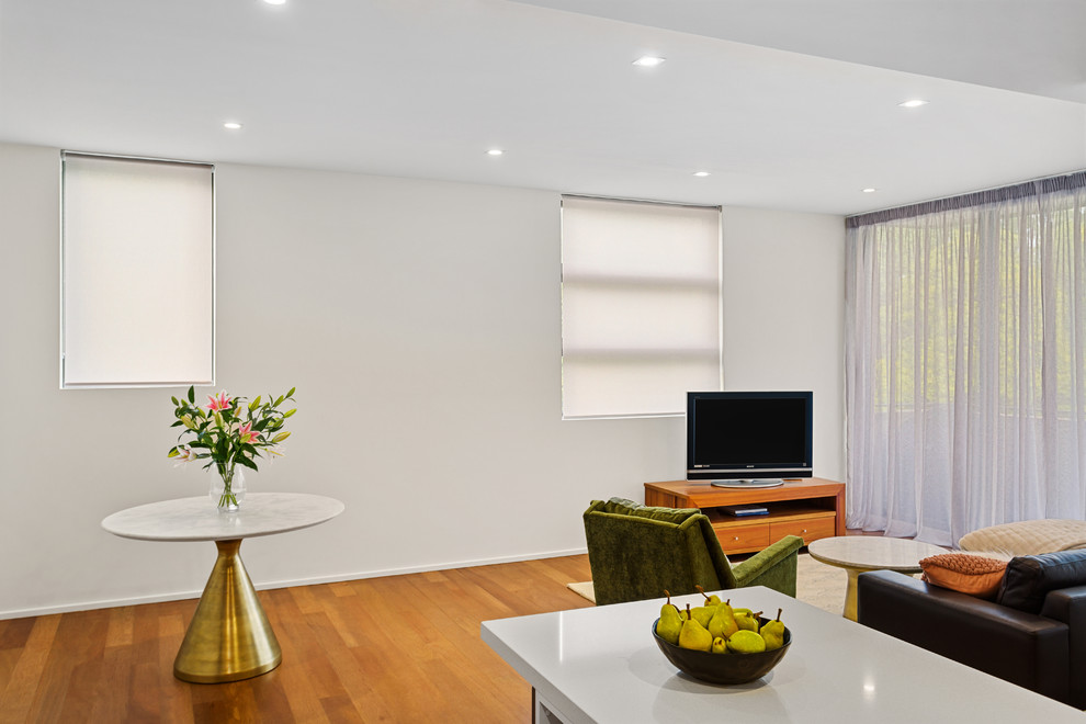 Inspiration for a medium sized contemporary open plan living room in Melbourne with white walls, medium hardwood flooring, a freestanding tv and brown floors.
