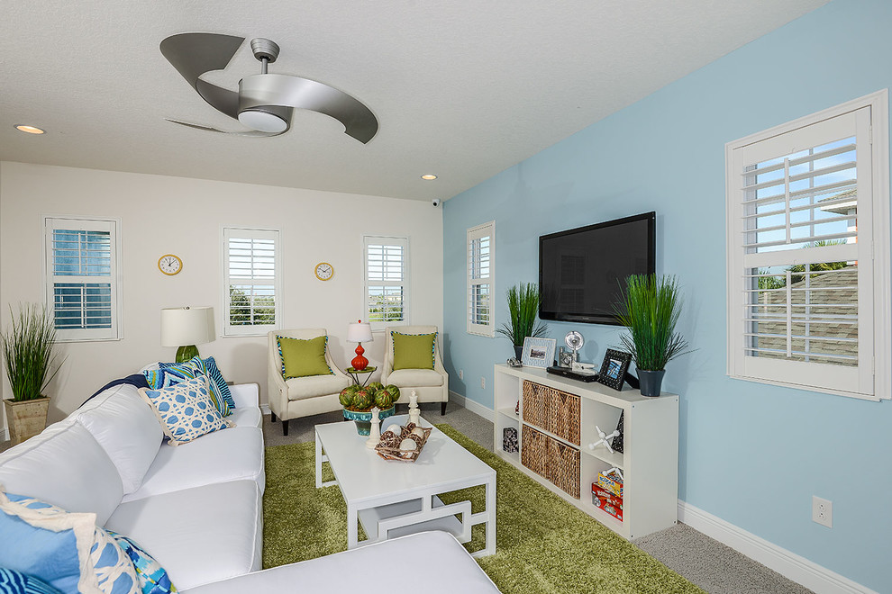 This is an example of a coastal living room in Tampa with blue walls, carpet and a wall mounted tv.