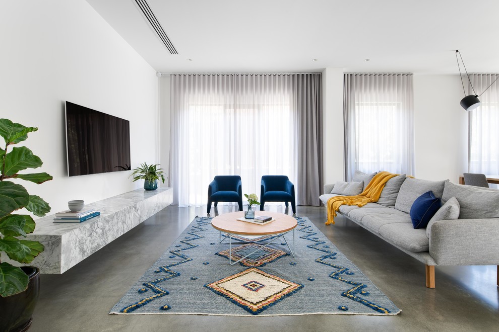 Идея дизайна: гостиная комната в скандинавском стиле с белыми стенами, бетонным полом, телевизором на стене и серым полом без камина