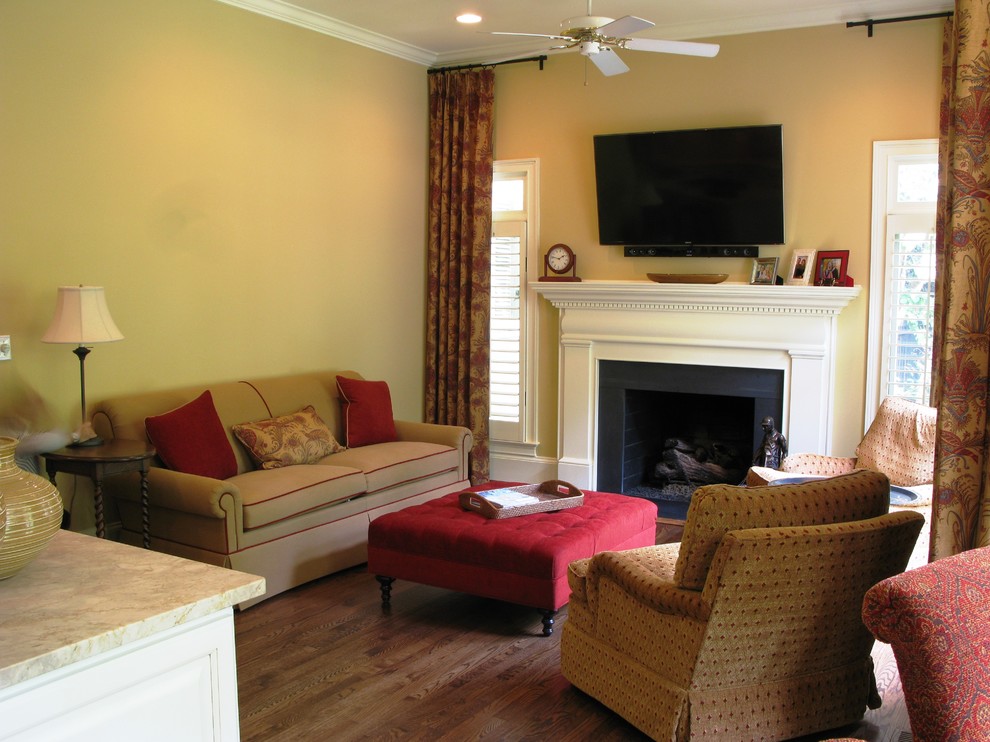 Cette image montre un petit salon traditionnel ouvert avec un mur beige, un sol en bois brun, une cheminée standard, un manteau de cheminée en pierre et un téléviseur fixé au mur.