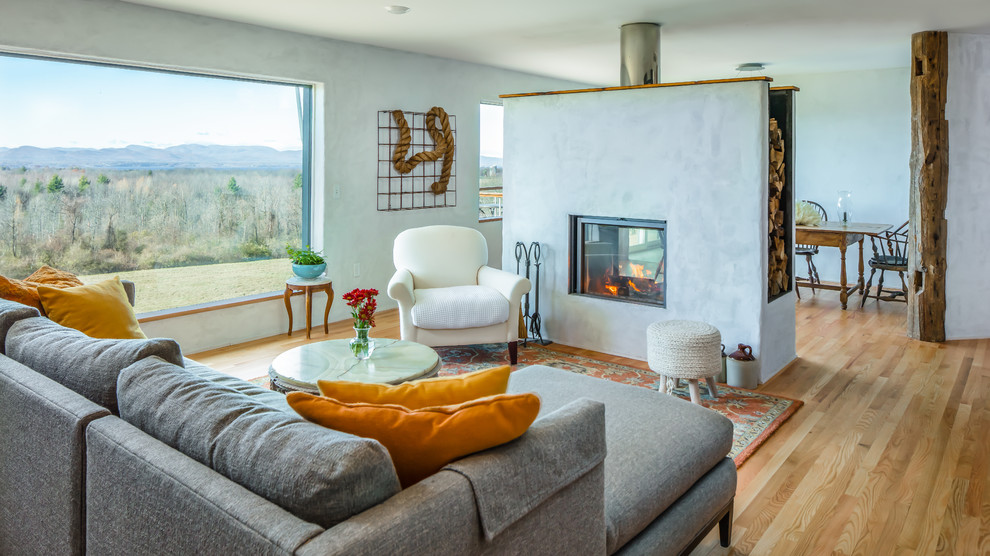 Photo of a country living room in Burlington with white walls, medium hardwood flooring, a two-sided fireplace and brown floors.