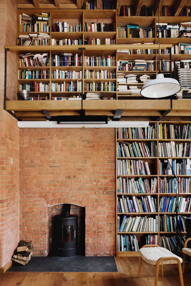 Bild på ett funkis vardagsrum, med ett bibliotek, mellanmörkt trägolv, en öppen vedspis och brunt golv