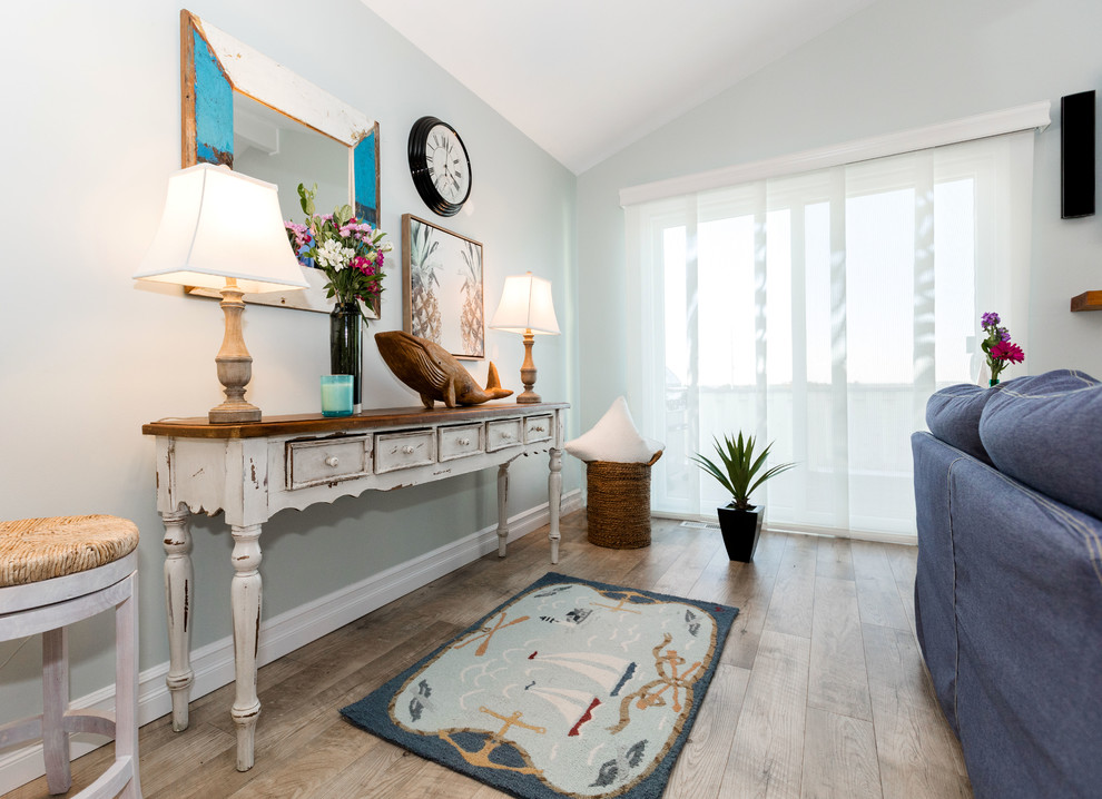 Стильный дизайн: большая парадная, открытая гостиная комната в морском стиле с синими стенами, полом из ламината, стандартным камином, фасадом камина из дерева, телевизором на стене и коричневым полом - последний тренд