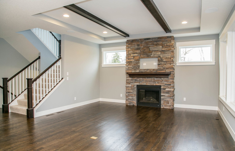 Photo of a classic open plan living room in Minneapolis with grey walls, medium hardwood flooring, a standard fireplace, a stone fireplace surround and a wall mounted tv.