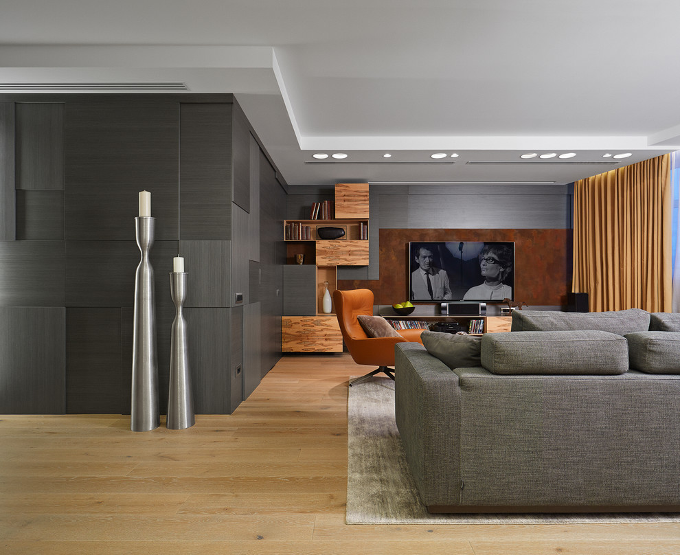 Стильный дизайн: гостиная комната в современном стиле с серыми стенами, светлым паркетным полом и телевизором на стене без камина - последний тренд