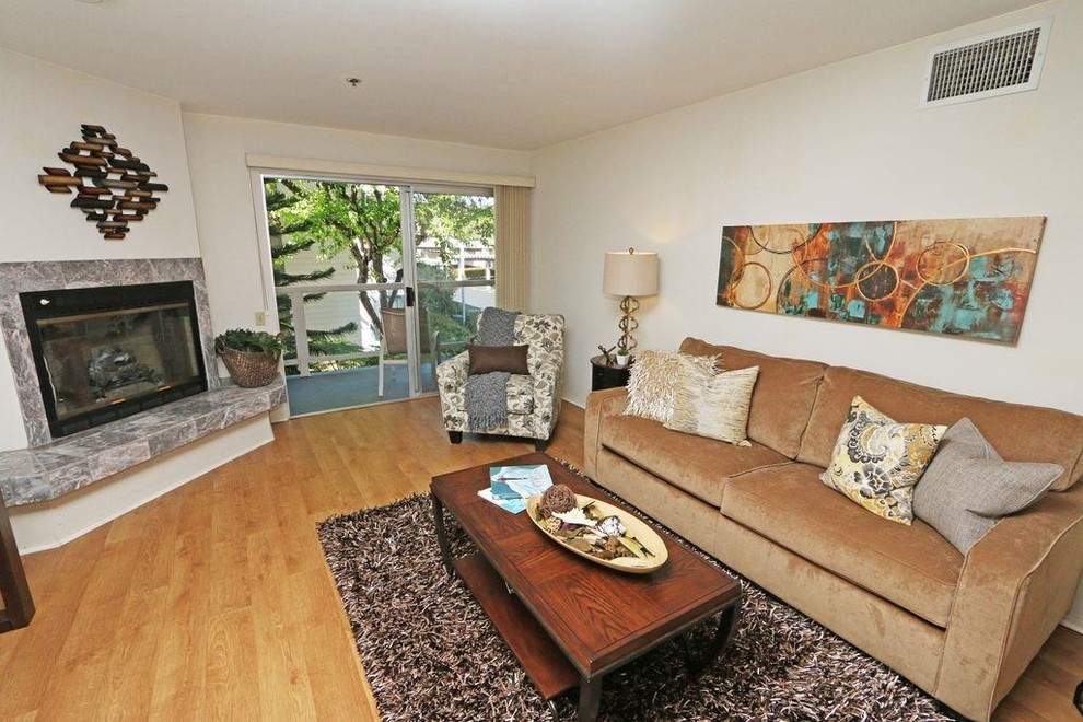 Klassisches Wohnzimmer mit weißer Wandfarbe, braunem Holzboden, Eckkamin und gefliester Kaminumrandung in San Diego