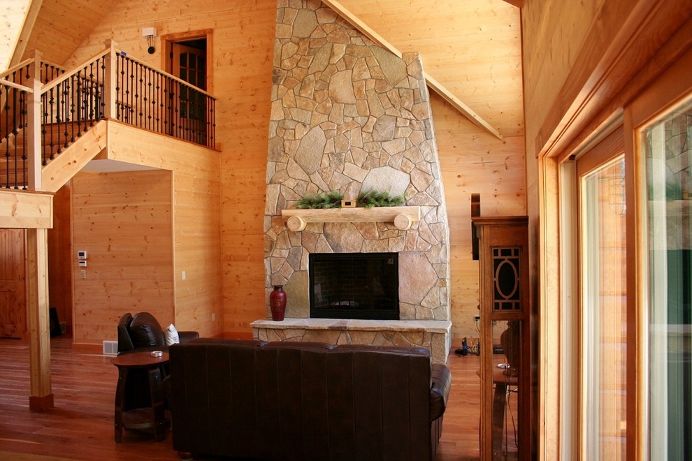 Offenes Uriges Wohnzimmer mit brauner Wandfarbe, braunem Holzboden, Kamin, Kaminumrandung aus Stein und braunem Boden in Sonstige