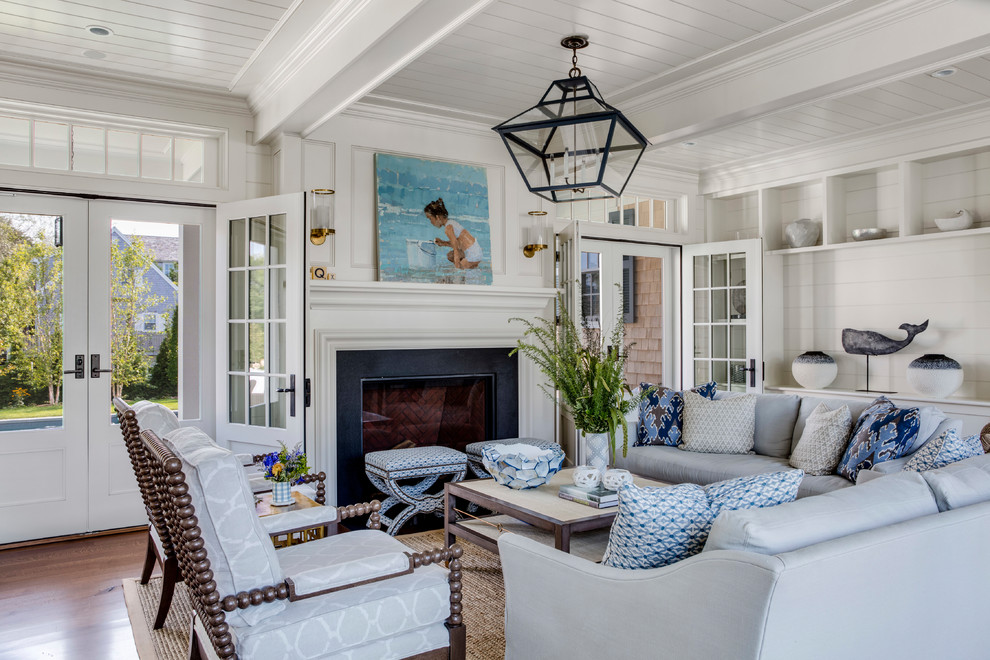 Immagine di un soggiorno costiero con sala formale, pareti bianche, pavimento in legno massello medio, camino classico e tappeto