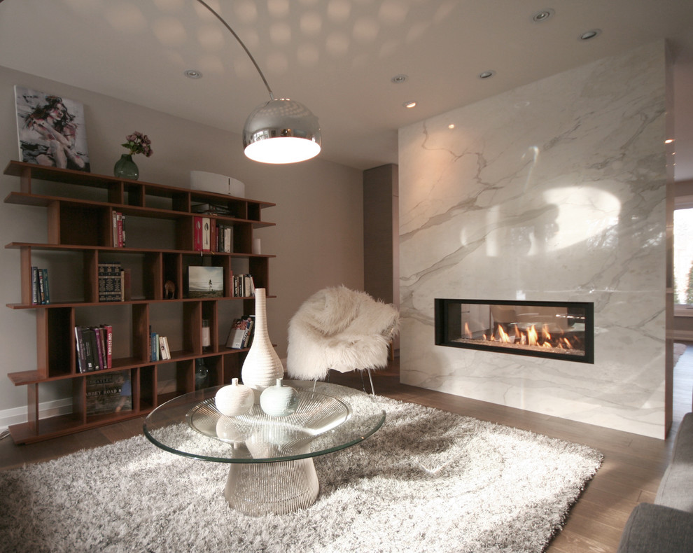 トロントにある中くらいなコンテンポラリースタイルのおしゃれなLDK (グレーの壁、無垢フローリング、両方向型暖炉、タイルの暖炉まわり、茶色い床) の写真