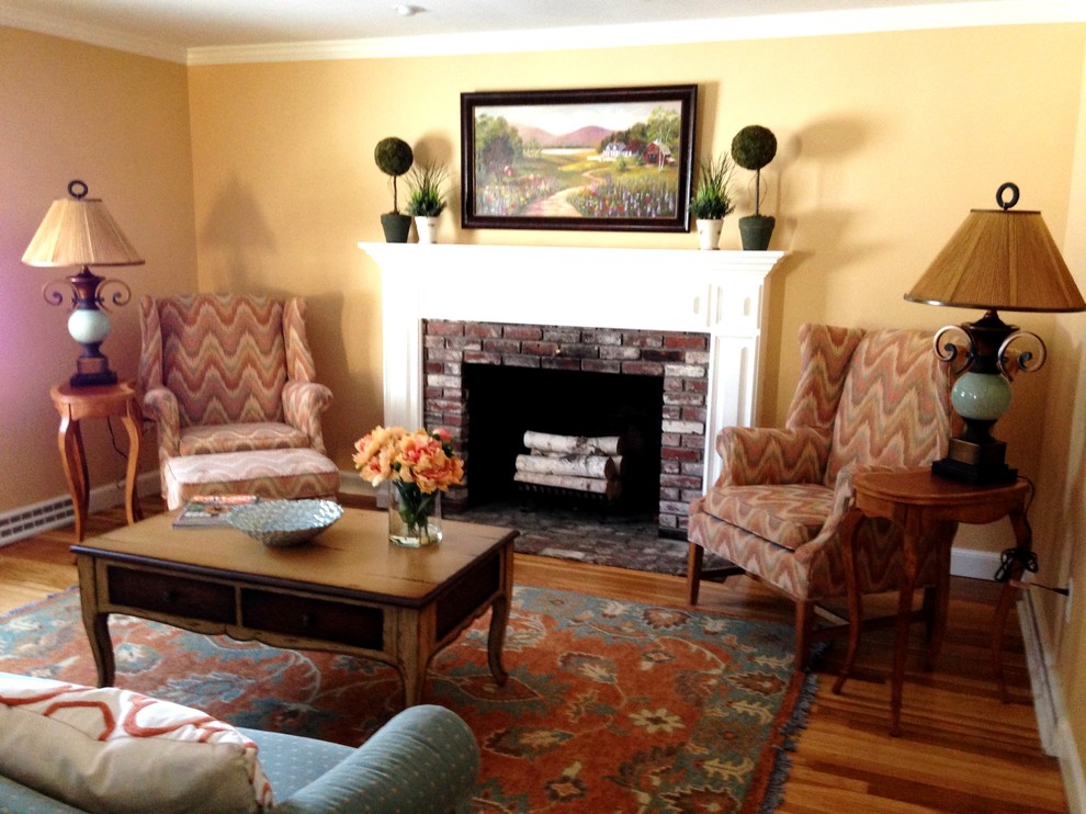 Photo of a medium sized traditional enclosed living room in Boston with yellow walls, medium hardwood flooring, a standard fireplace and a brick fireplace surround.