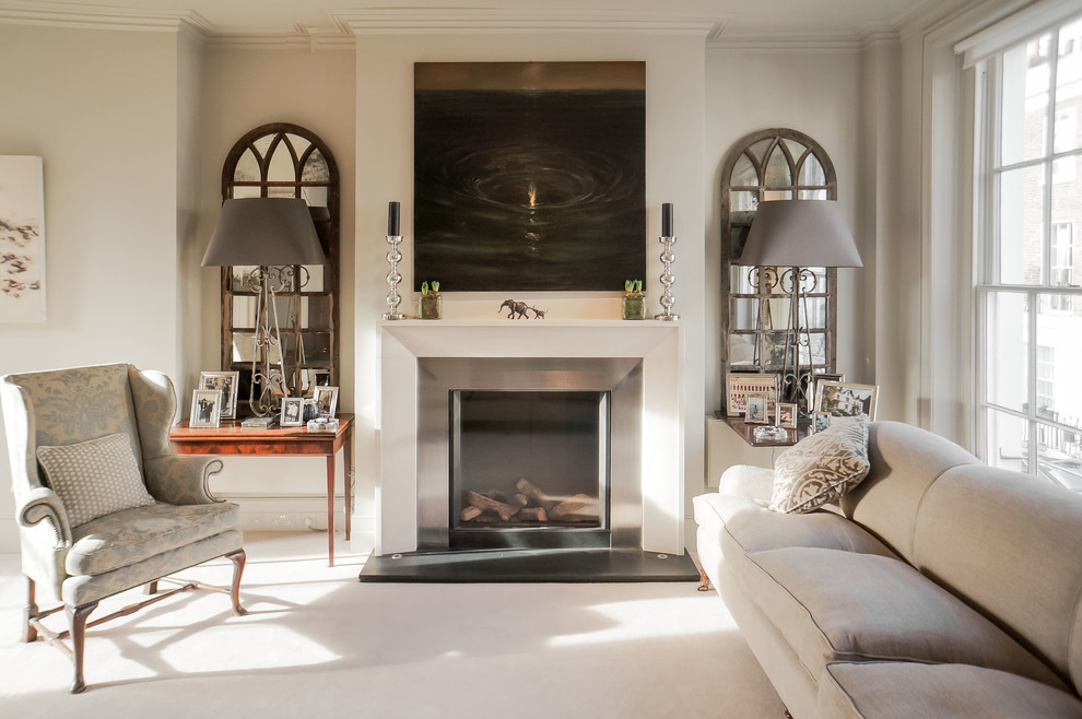 Inspiration for a medium sized classic formal living room in London with beige walls, a standard fireplace, no tv, a metal fireplace surround, carpet and feature lighting.