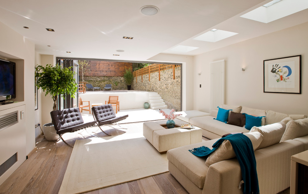 Modernes Wohnzimmer mit beiger Wandfarbe und braunem Holzboden in London