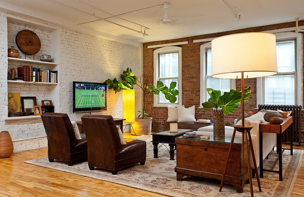 Idée de décoration pour un salon urbain avec un sol en bois brun et un téléviseur fixé au mur.