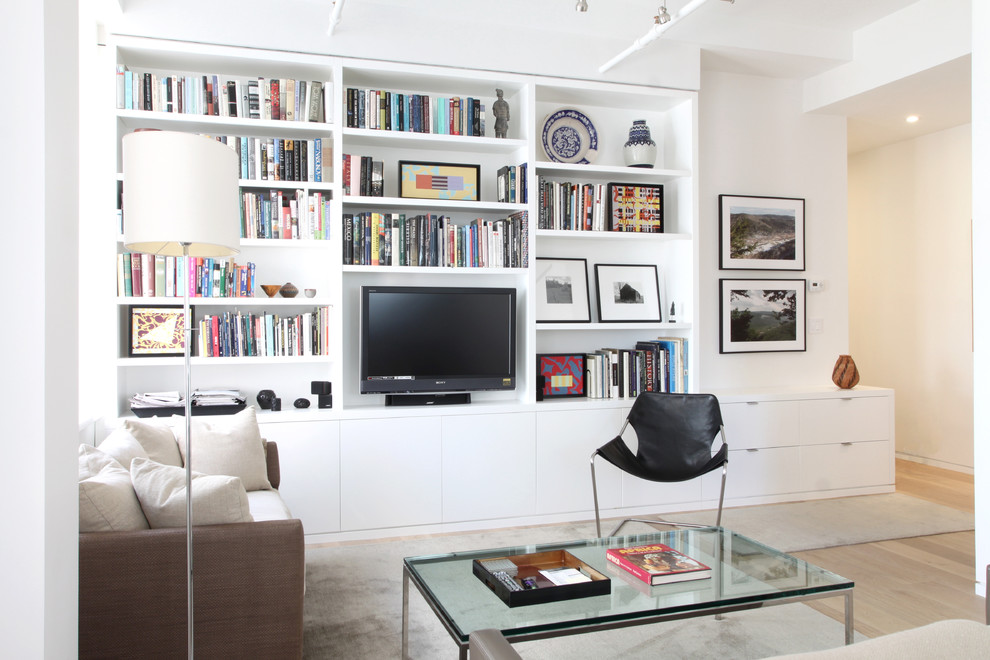 Diseño de salón abierto actual de tamaño medio con paredes blancas, suelo de madera clara y pared multimedia