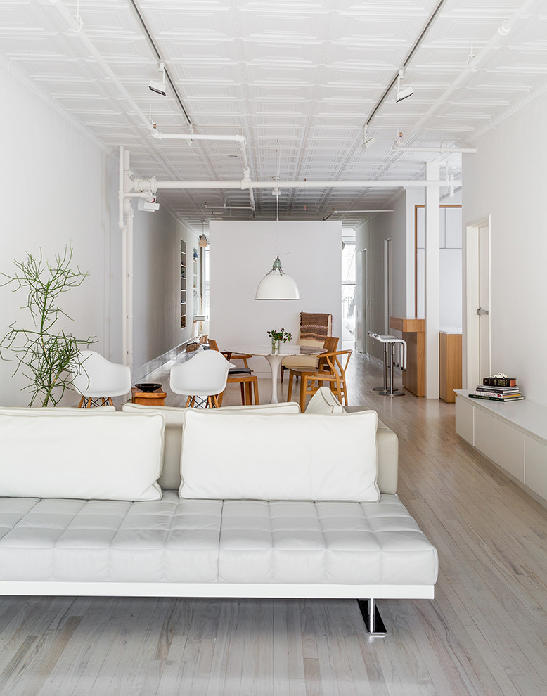 Foto de salón abierto minimalista de tamaño medio con paredes blancas y suelo de madera clara