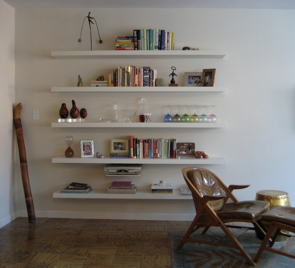 Imagen de biblioteca en casa abierta vintage de tamaño medio sin chimenea con paredes blancas, suelo marrón, suelo de madera en tonos medios y televisor colgado en la pared