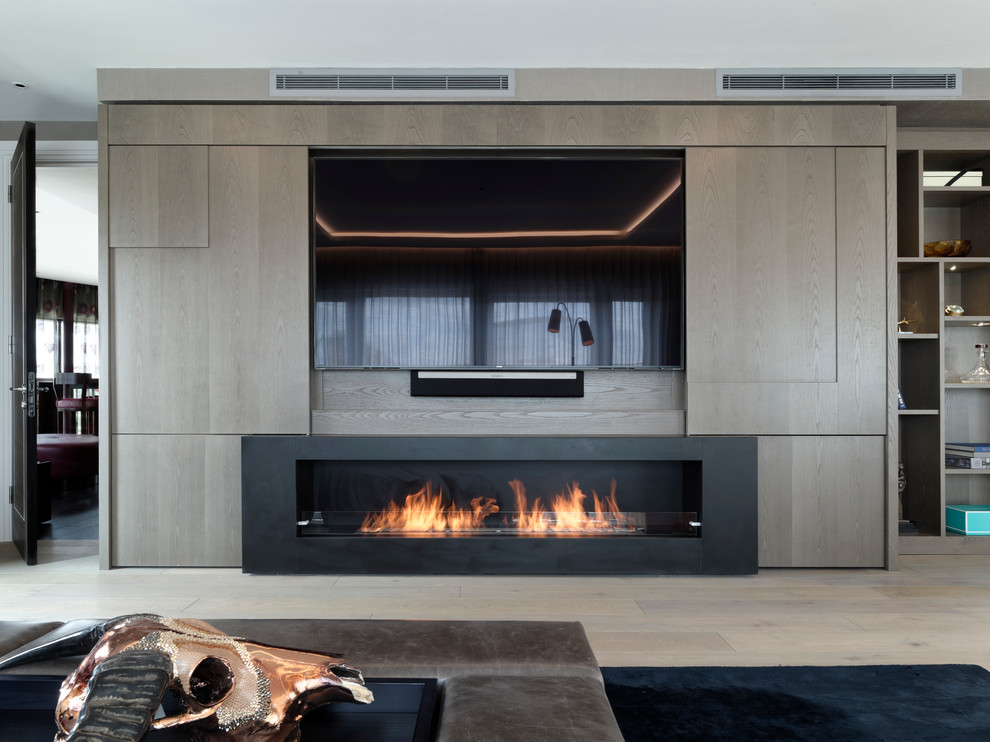 This is an example of a large contemporary formal open plan living room in London with a ribbon fireplace and a built-in media unit.
