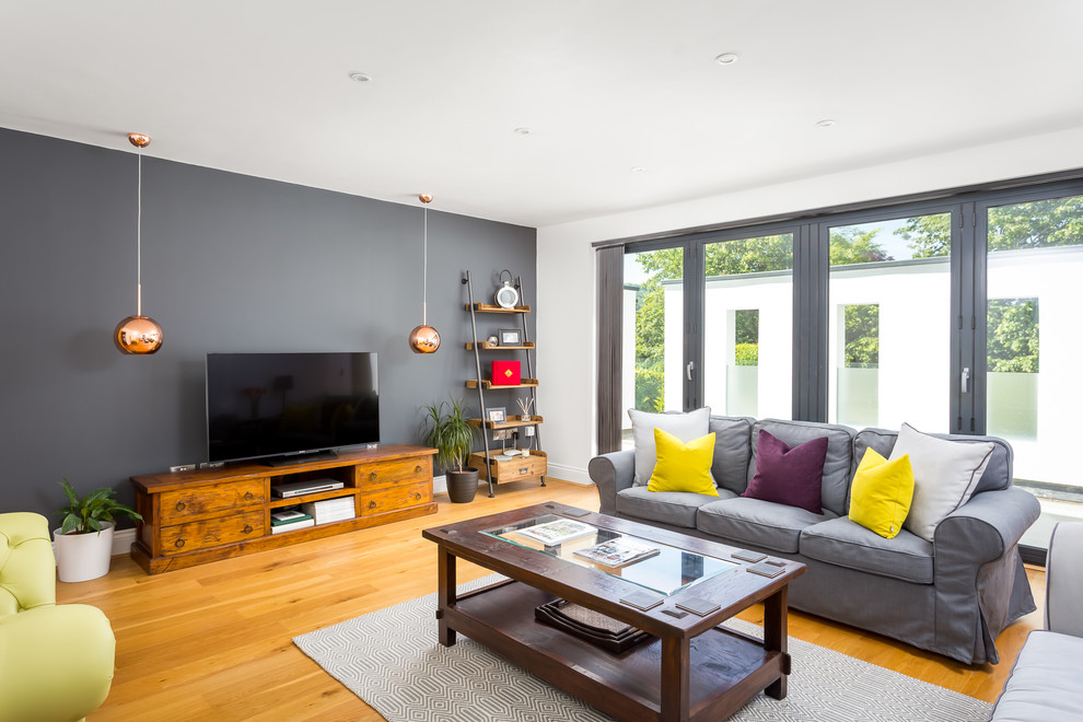 This is an example of a medium sized contemporary formal enclosed living room in Gloucestershire with white walls, light hardwood flooring, no fireplace and a freestanding tv.