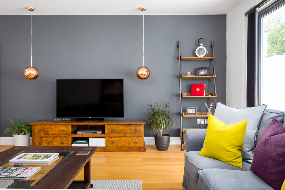 Inredning av ett modernt mellanstort separat vardagsrum, med ljust trägolv, en fristående TV och grå väggar