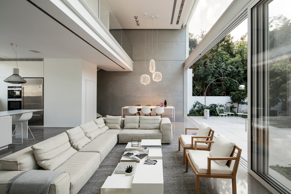 На фото: открытая гостиная комната в современном стиле с серыми стенами и бетонным полом с