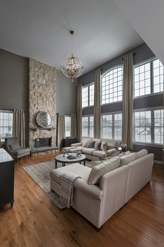 This is an example of a large traditional formal open plan living room in Philadelphia with grey walls, medium hardwood flooring, a standard fireplace, a stone fireplace surround, a freestanding tv and brown floors.