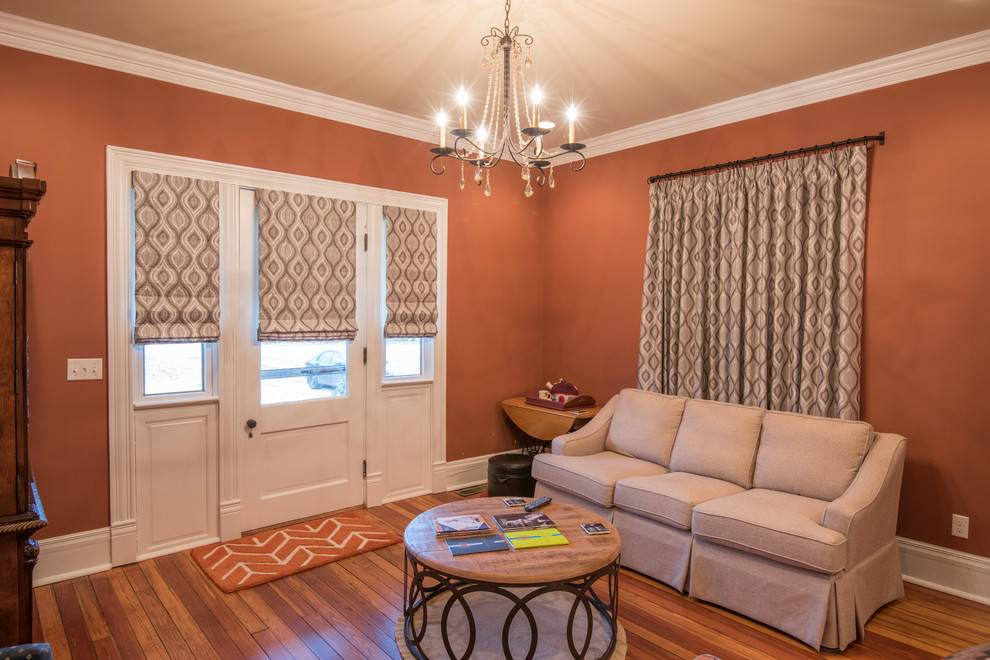 Esempio di un soggiorno minimal di medie dimensioni e chiuso con pareti arancioni, pavimento in legno massello medio, nessun camino e nessuna TV