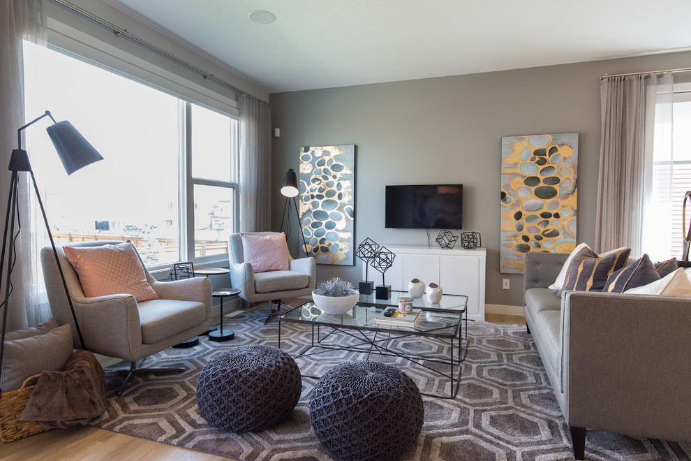 Foto de salón para visitas contemporáneo de tamaño medio sin chimenea con paredes grises, suelo de madera clara, televisor colgado en la pared y suelo beige