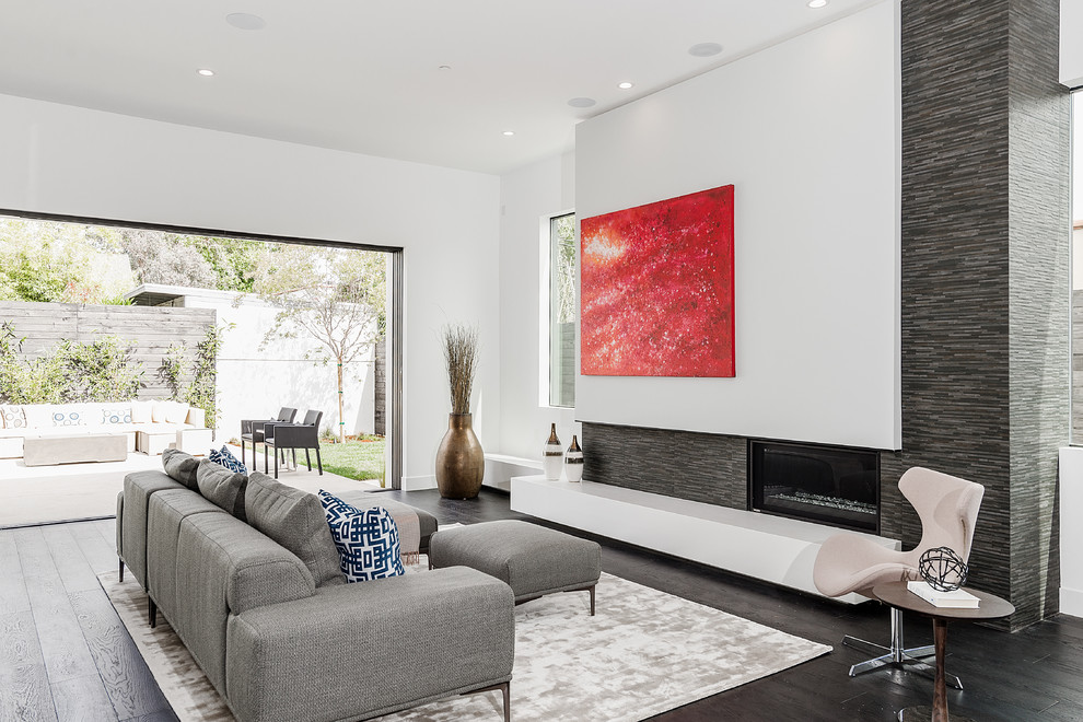 Cette image montre un grand salon design ouvert avec un mur blanc, parquet foncé, une cheminée standard, un manteau de cheminée en béton et un téléviseur dissimulé.