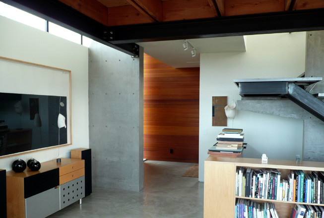 Réalisation d'un grand salon minimaliste fermé avec une salle de réception, un mur gris, sol en béton ciré, aucune cheminée, un téléviseur fixé au mur et un sol gris.