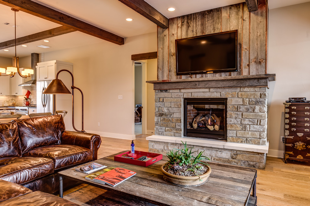 Large mountain style open concept light wood floor living room photo in Austin with a standard fireplace, a stone fireplace and a wall-mounted tv