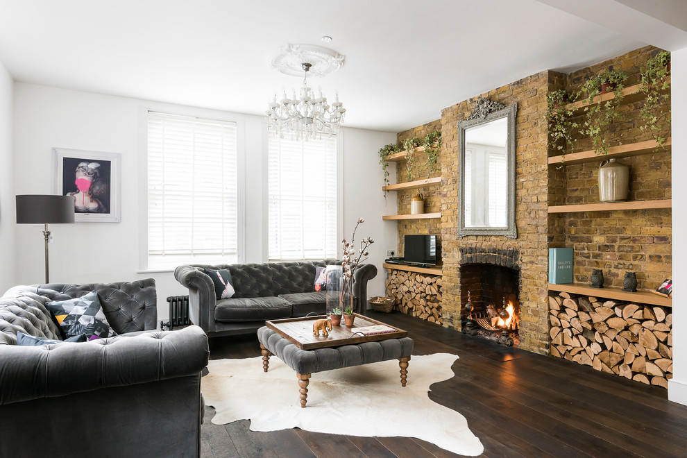 Inspiration for a medium sized enclosed living room feature wall in London with white walls, dark hardwood flooring, a standard fireplace, a brick fireplace surround, a freestanding tv and brown floors.