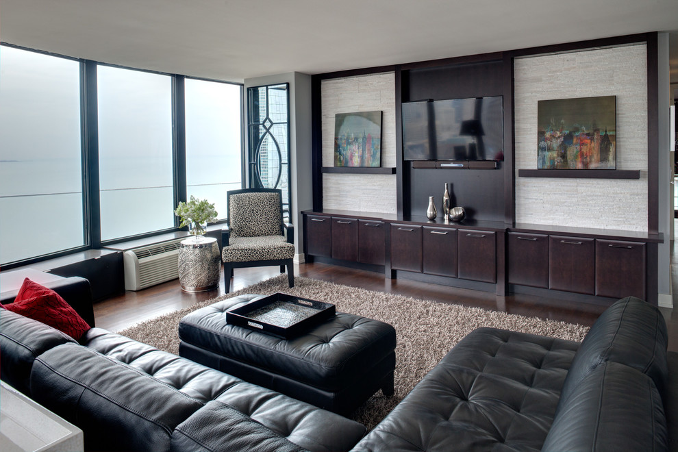 Modelo de salón abierto contemporáneo sin chimenea con suelo de madera oscura y televisor colgado en la pared