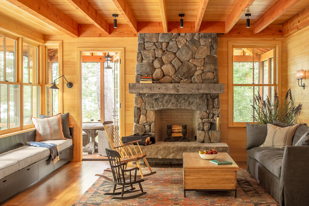 Rustikales Wohnzimmer mit braunem Holzboden, Kamin, Kaminumrandung aus Stein und braunem Boden in Portland Maine