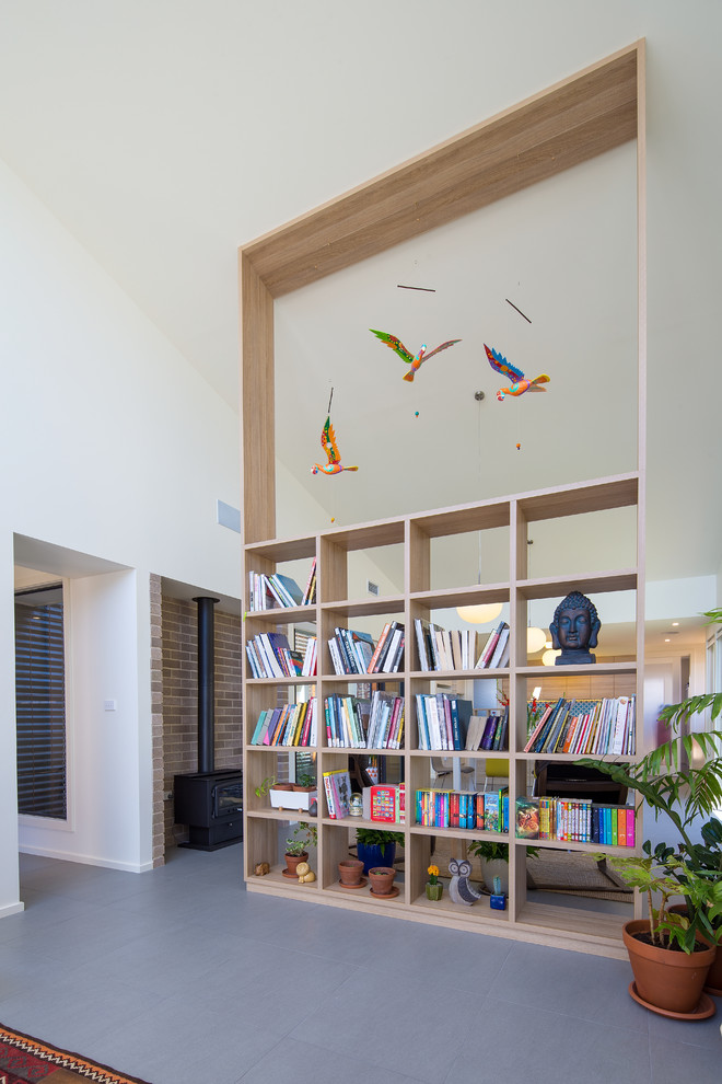 Aménagement d'un salon contemporain de taille moyenne et ouvert avec une bibliothèque ou un coin lecture, un poêle à bois, un manteau de cheminée en brique et un sol gris.