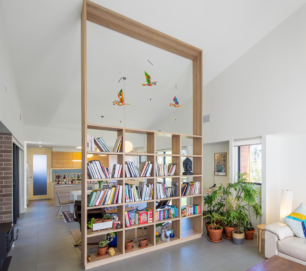 Idéer för mellanstora funkis allrum med öppen planlösning, med ett bibliotek, grått golv och vita väggar