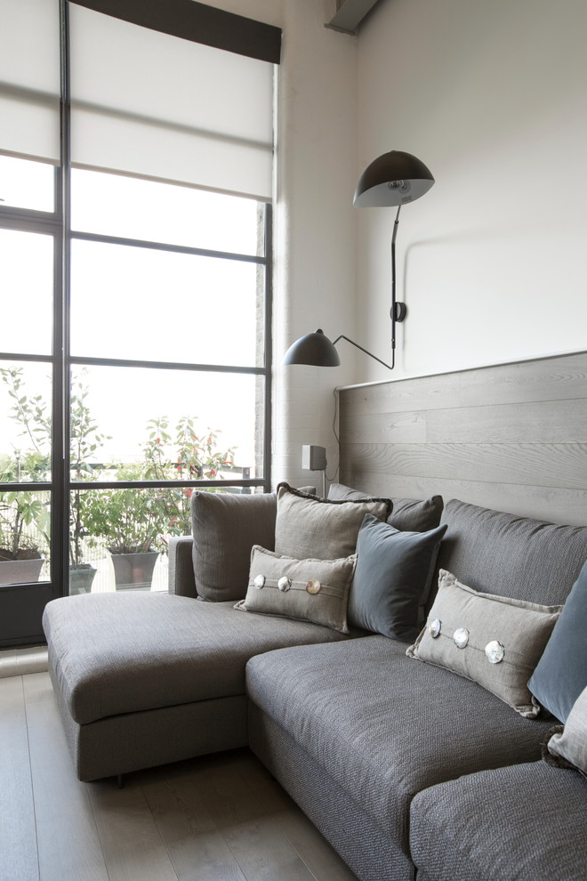 Esempio di un soggiorno industriale di medie dimensioni e aperto con pareti bianche, parquet chiaro e parete attrezzata