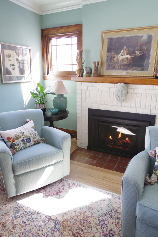 Aménagement d'un salon craftsman de taille moyenne et fermé avec un mur bleu, parquet clair, une cheminée standard, un manteau de cheminée en brique et un sol beige.