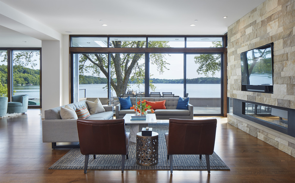 Offenes Modernes Wohnzimmer mit weißer Wandfarbe, dunklem Holzboden, Gaskamin, Kaminumrandung aus Stein und braunem Boden in Minneapolis