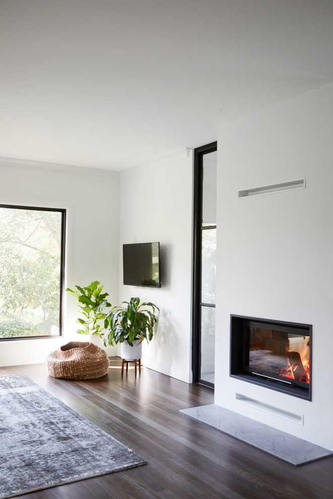Großes, Offenes Skandinavisches Wohnzimmer mit weißer Wandfarbe, dunklem Holzboden, Tunnelkamin, verputzter Kaminumrandung, TV-Wand und schwarzem Boden in Wollongong