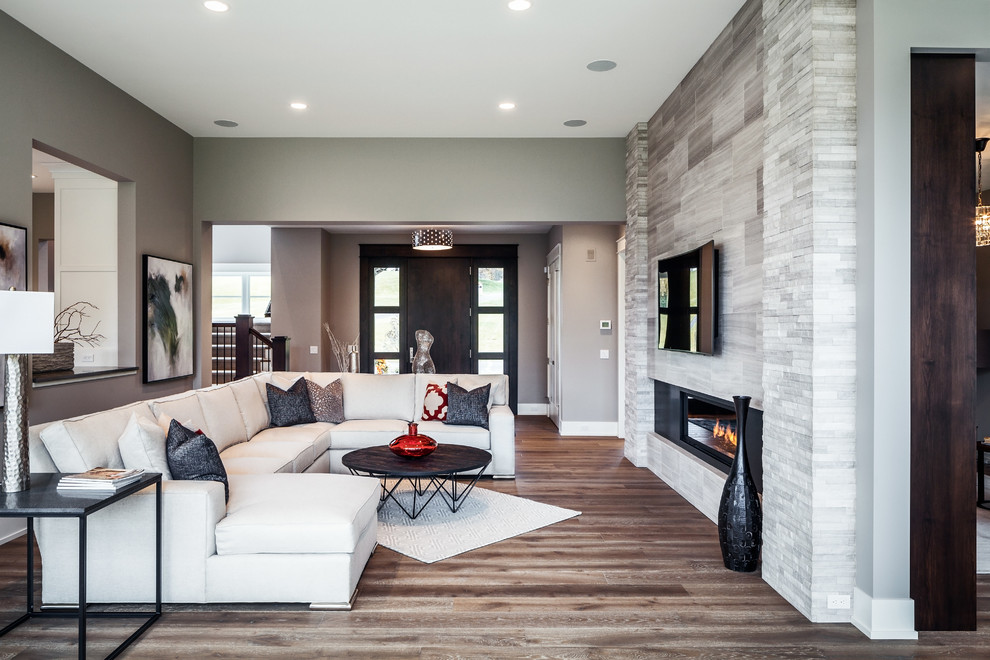 Example of a large transitional formal light wood floor living room design in Grand Rapids with gray walls, a ribbon fireplace, a stone fireplace and a wall-mounted tv