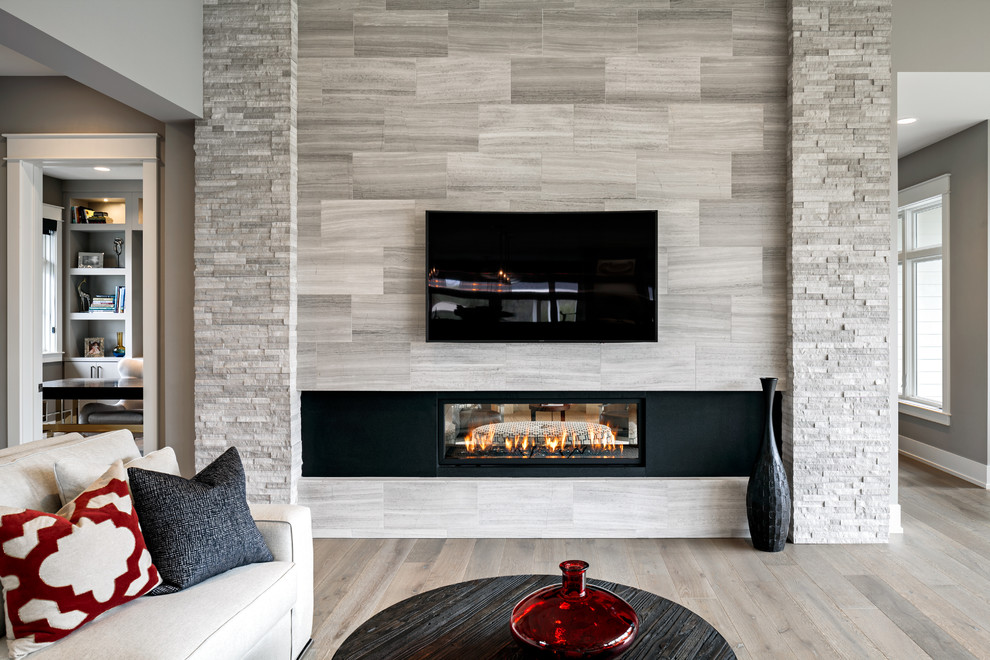 Inspiration for a large transitional formal light wood floor living room remodel in Grand Rapids with gray walls, a ribbon fireplace, a stone fireplace and a wall-mounted tv