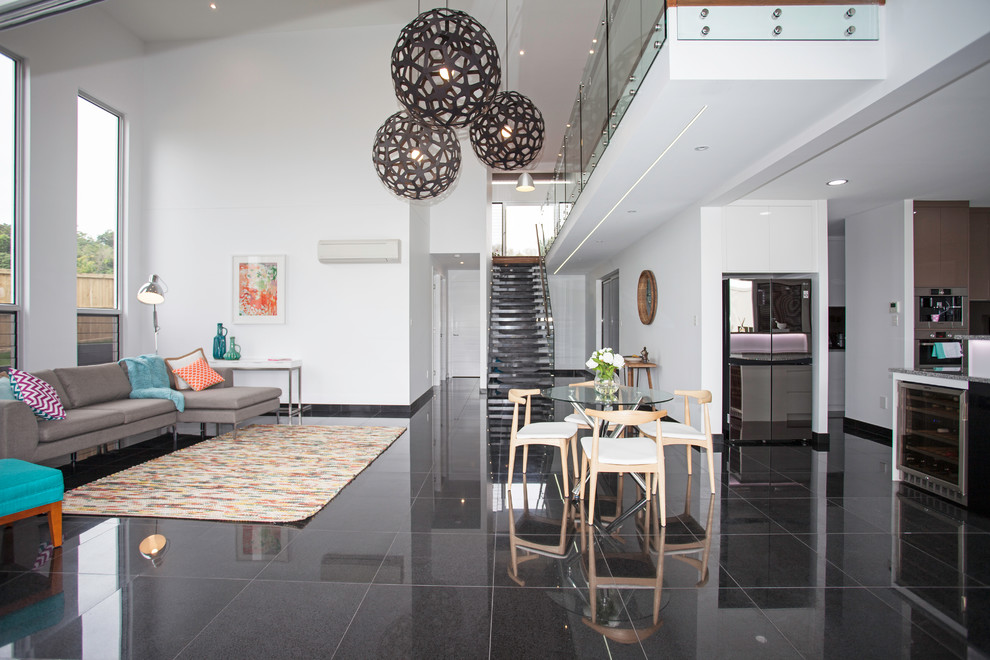 Стильный дизайн: большая парадная, открытая гостиная комната в современном стиле с белыми стенами, полом из керамической плитки и черным полом - последний тренд