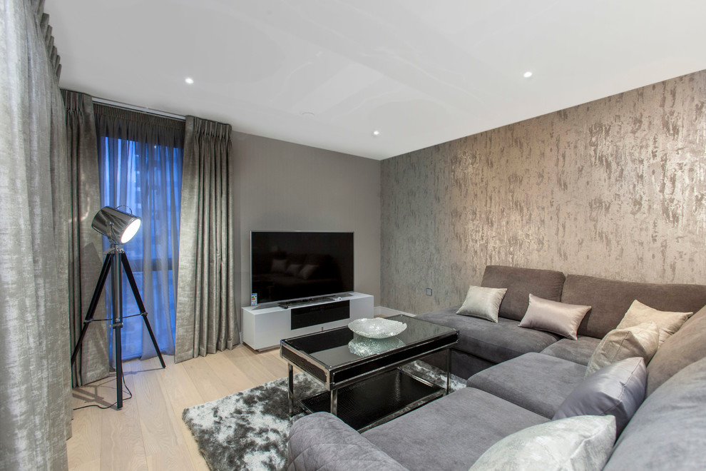 На фото: большая открытая гостиная комната в современном стиле с серыми стенами, светлым паркетным полом и отдельно стоящим телевизором
