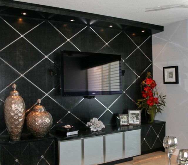 Modelo de salón cerrado contemporáneo de tamaño medio con paredes negras, televisor colgado en la pared y suelo beige
