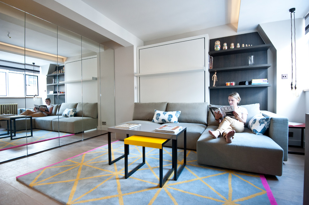 Small trendy enclosed light wood floor living room library photo in London with gray walls and no fireplace