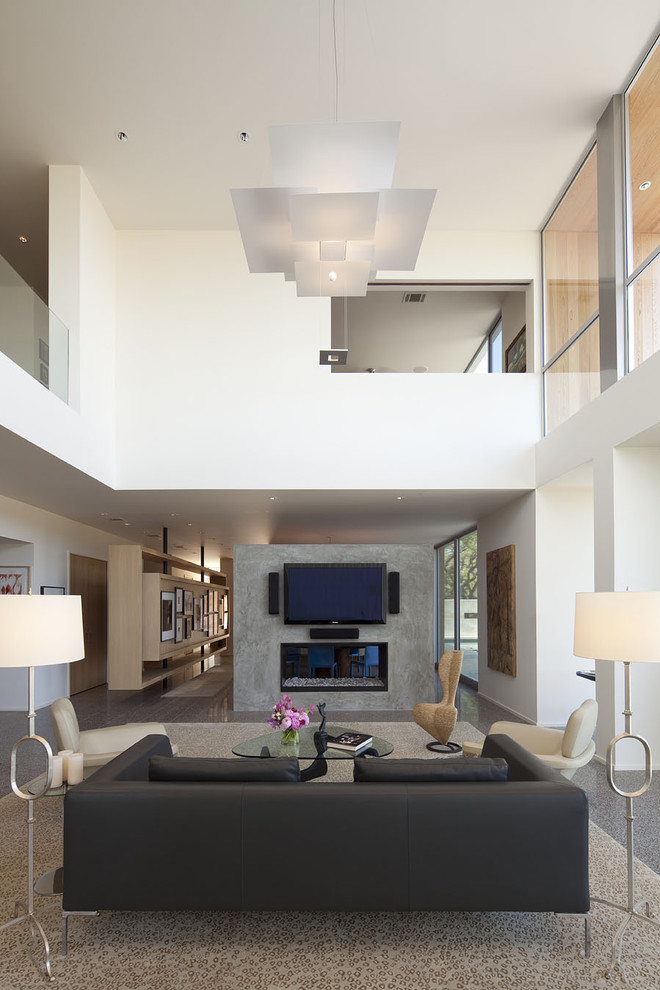 Свежая идея для дизайна: большая открытая гостиная комната:: освещение в современном стиле с телевизором на стене, белыми стенами, бетонным полом, двусторонним камином, фасадом камина из бетона и ковром на полу - отличное фото интерьера
