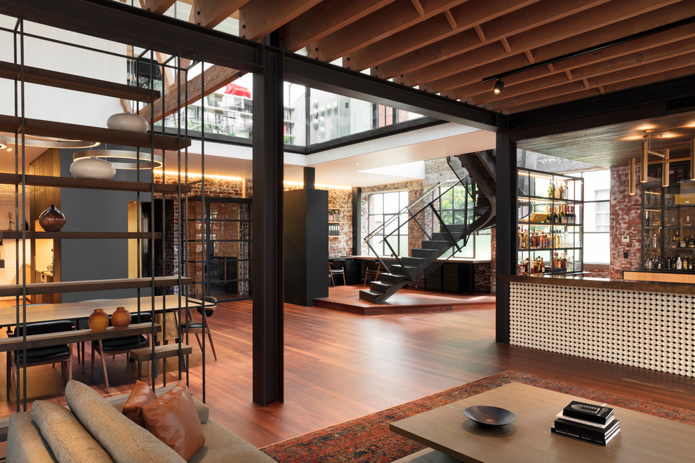Ispirazione per un grande soggiorno industriale aperto con angolo bar, pavimento in legno massello medio, nessuna TV e pavimento marrone